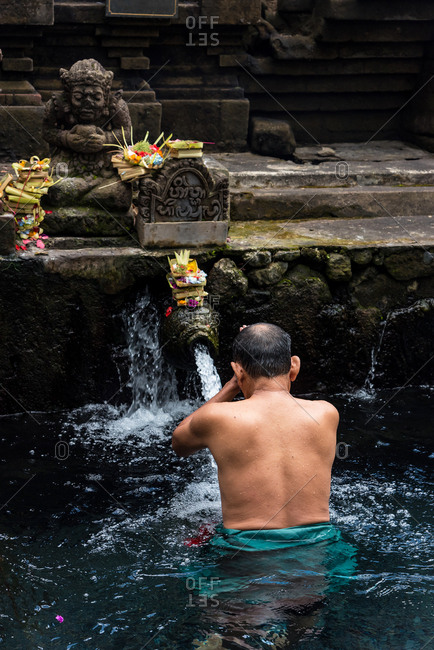 man bathing in the waters of the Tirta Empul Water Temple, Ubud, Bali