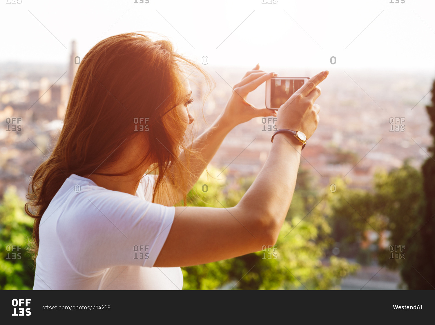 Italy- Verona- Italy- Verona- redheaded woman taking photo with smartphone by sunset