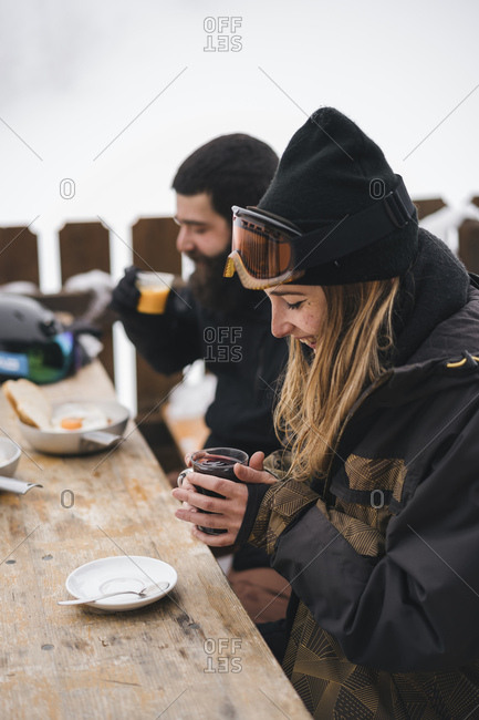 Couple in skiwear having a hot drink at mountain lodge