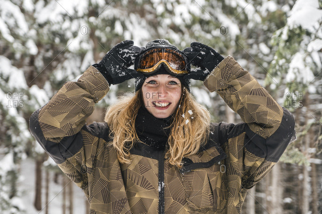 Portrait of happy young woman in skiwear in winter forest