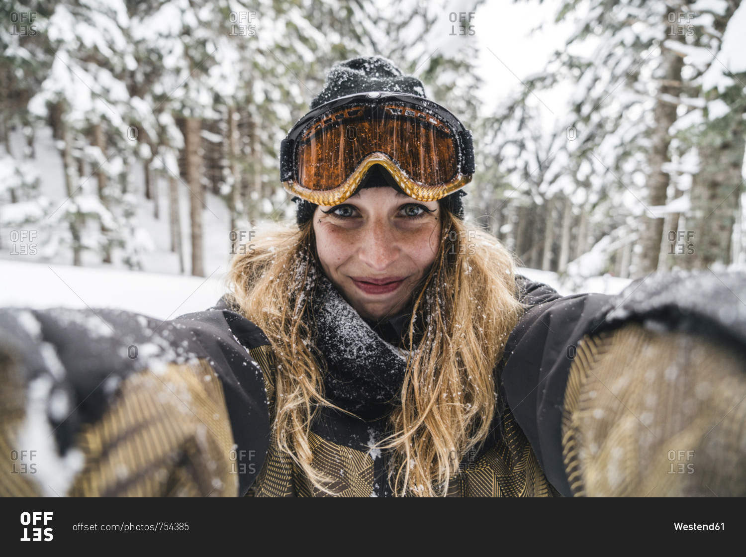Portrait of smiling young woman in skiwear in winter forest