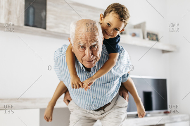 Portrait of grandfather giving his grandson a piggyback ride in the living room