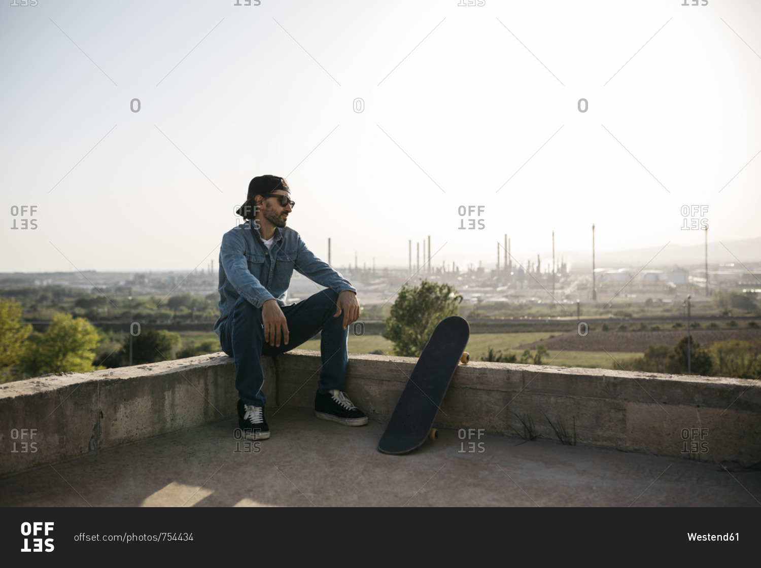 Skateboarder dressed in casual clothes resting at sunset stock photo ...