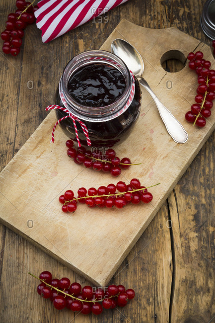 Jam jar of currant jelly and red currants on wooden board