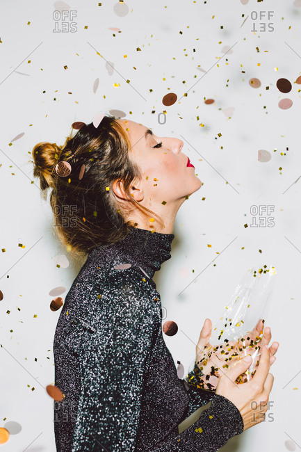 Beautiful woman blowing away gold confetti in a New Year party celebration.