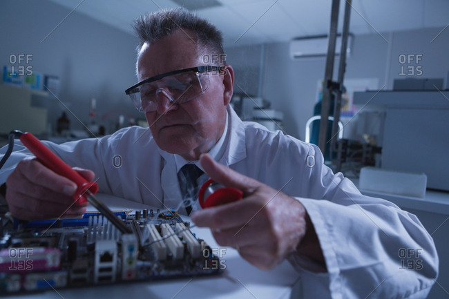 Male scientist soldering circuit board in laboratory