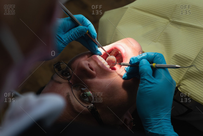 Female dentist examining a patient with tools in dental clinic
