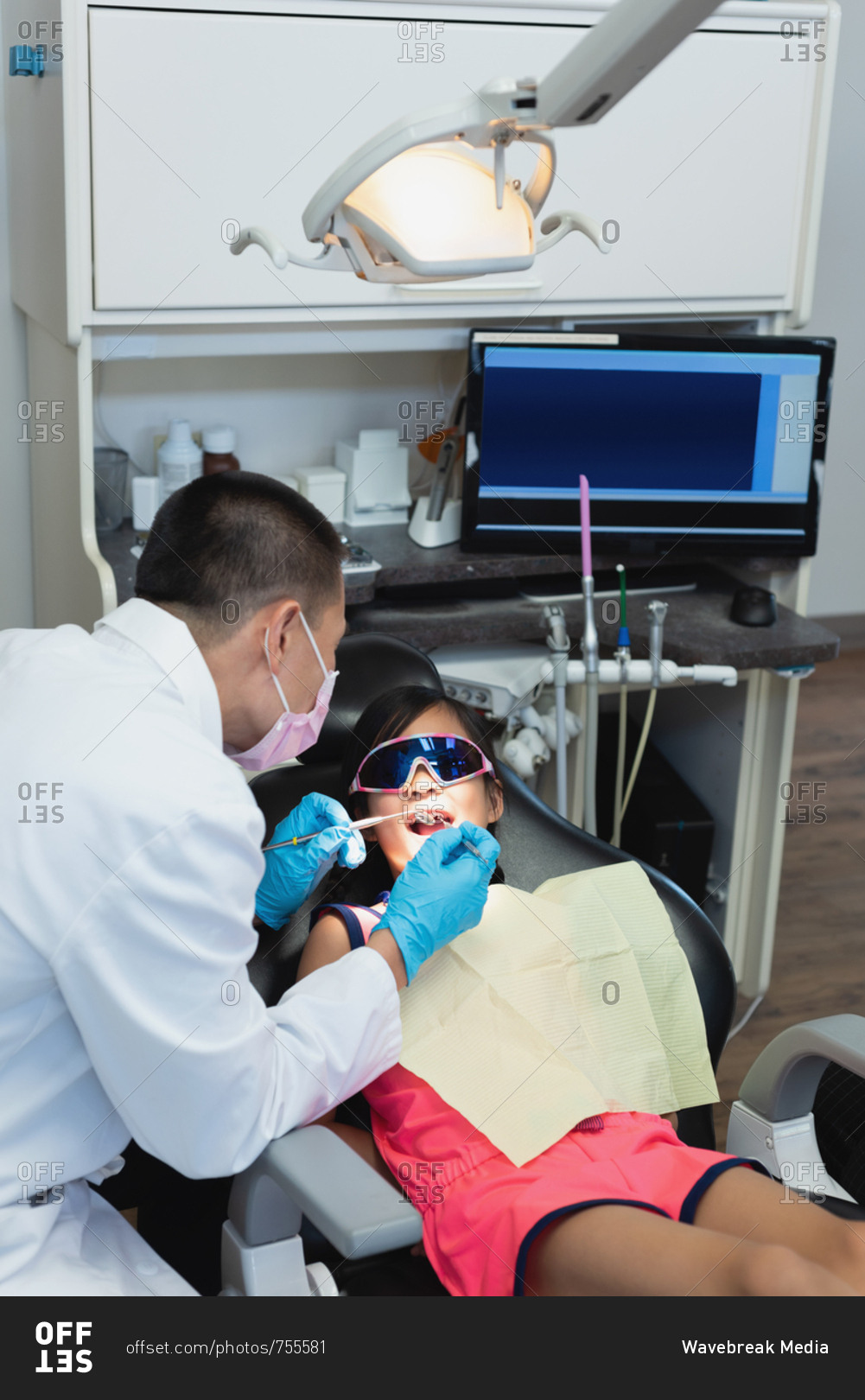 Male dentist examining a patient with tools in clinic