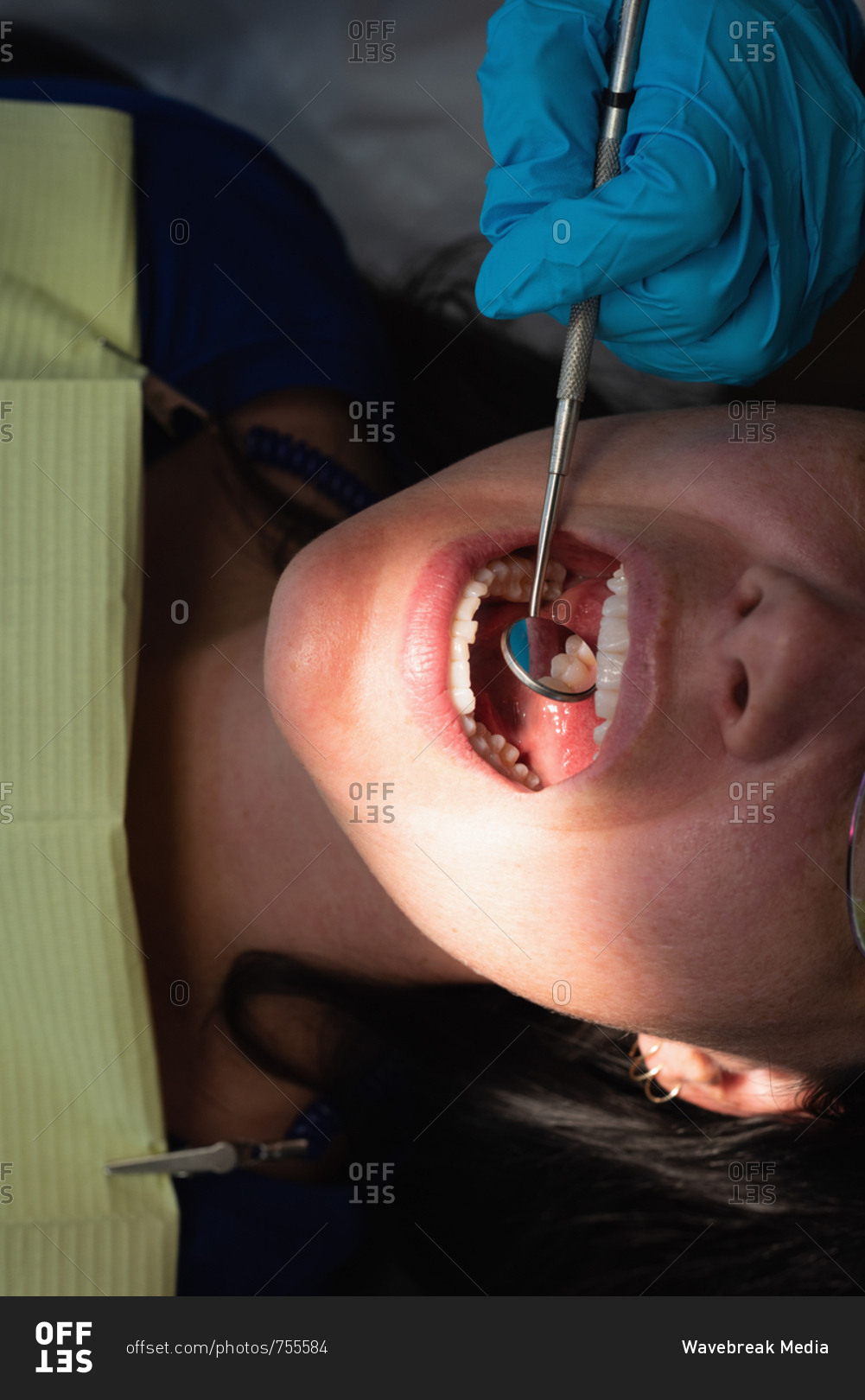Close-up of male dentist examining a lady patient in clinic
