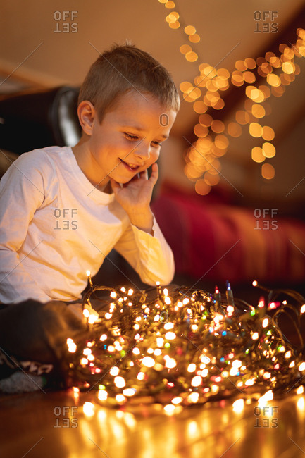 Smiling boy looking at illuminated fairy lights at home