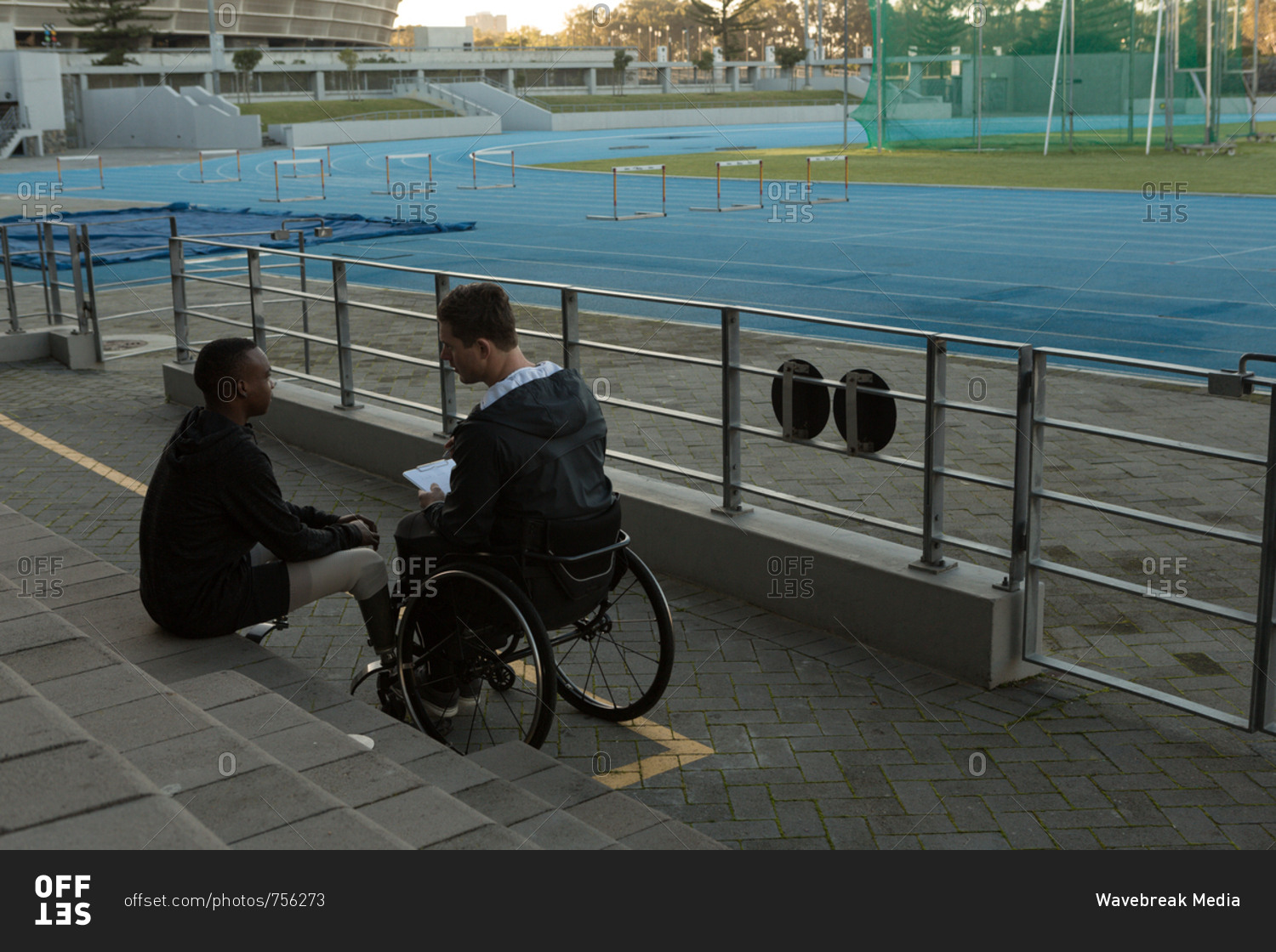 Two disabled athletics discussing over clipboard at sports venue