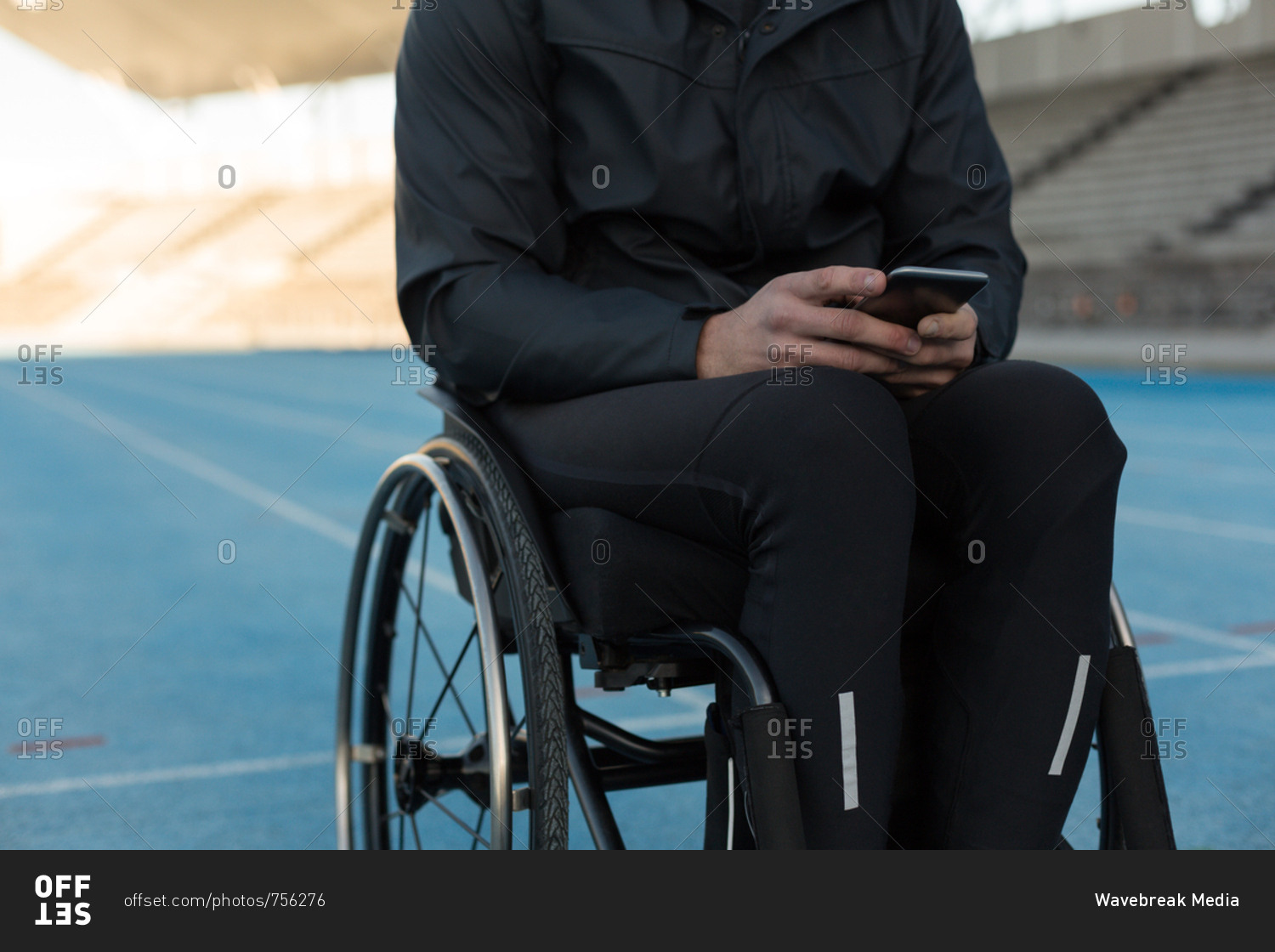 Mid section of disabled athletic using mobile phone at sports venue