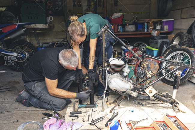 Mechanic repairing motorbike in repair garage