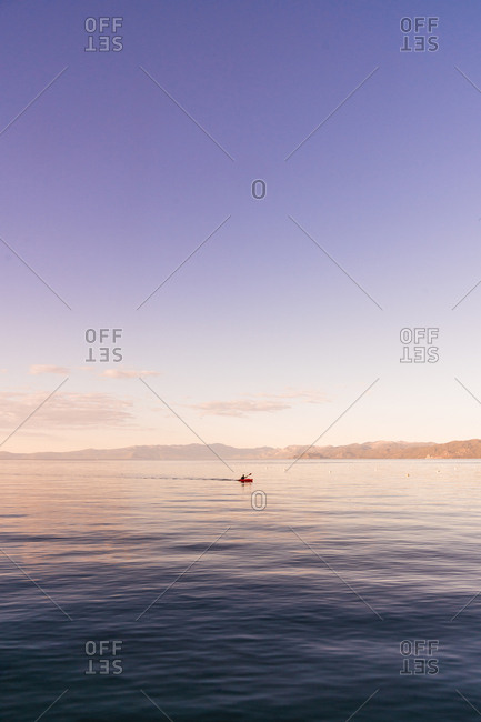 View of small figure of boat sailing on peaceful water of Lake Tahoe under blue sky in twilight, USA