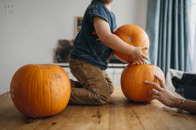Kid playing with pumpkins on table