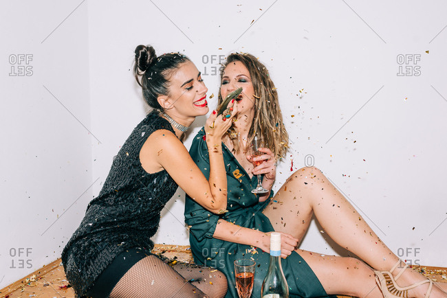 Two dressed up women celebrating New Year\'s Eve and wishing a happy New Year to someone on the phone