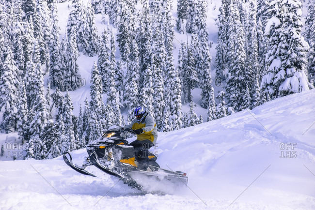 January 19, 2015: Side view of adventurous man jumping on snowmobile in Callaghan Valley, Whistler, British Columbia, Canada