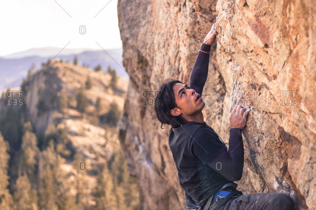 April 4, 2015: Side view shot of adventurous rock climber climbing cliff at Skaha Bluffs, Penticton, British Colombia, Canada