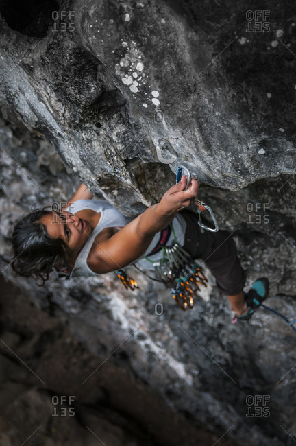 January 18, 2016: View from above of adventurous woman rock climbing up challenging cliff