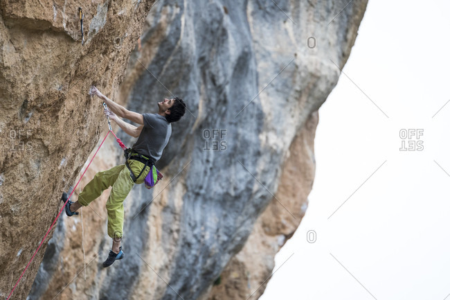 March 4, 2018: Side view of single adventurous man rock climbing up cliff, Siurana, Catalonia, Spain