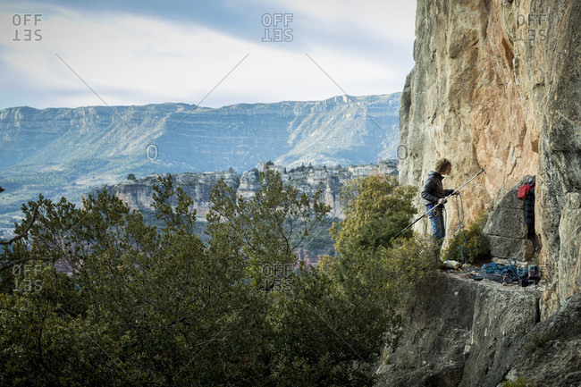 February 18, 2018: Distant view of single adventurous male rock climber preparing stick clip at cliff, Siurana, Catalonia, Spain