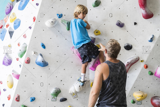 March 21, 2018: Rear view shot of father helping son with climbing wall