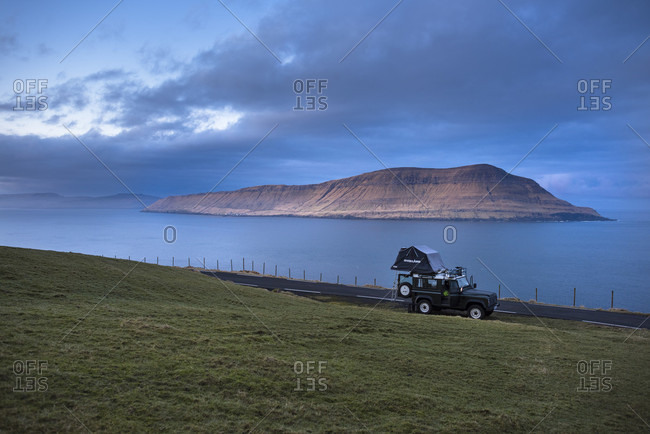 March 18, 2016: Side view of 4x4 car driving along coastline, Faroe Islands, Denmark
