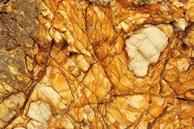 Sandstone with miraculous structures and forms in golden color on a beach in New Zealand.