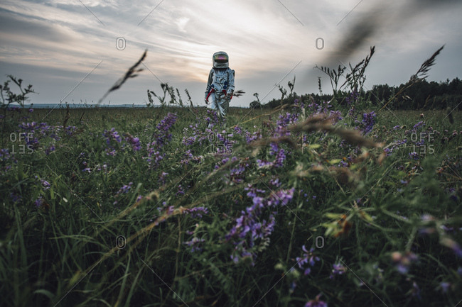 Spaceman exploring nature- standing in meadow- looking at sky