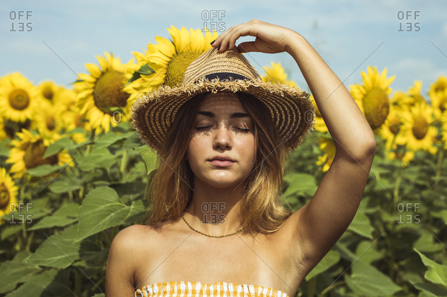 Girl Putting On A Straw Hat In A Sunflower Field Photograph by