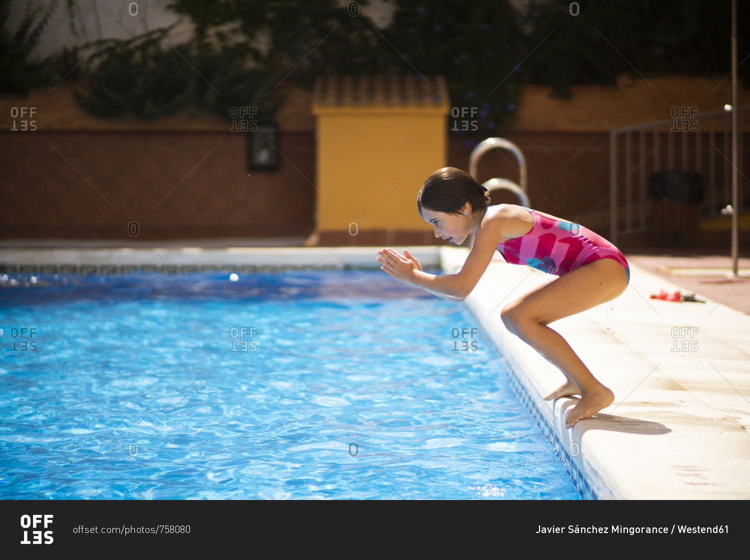 Young girl jumping head first into the pool in summer