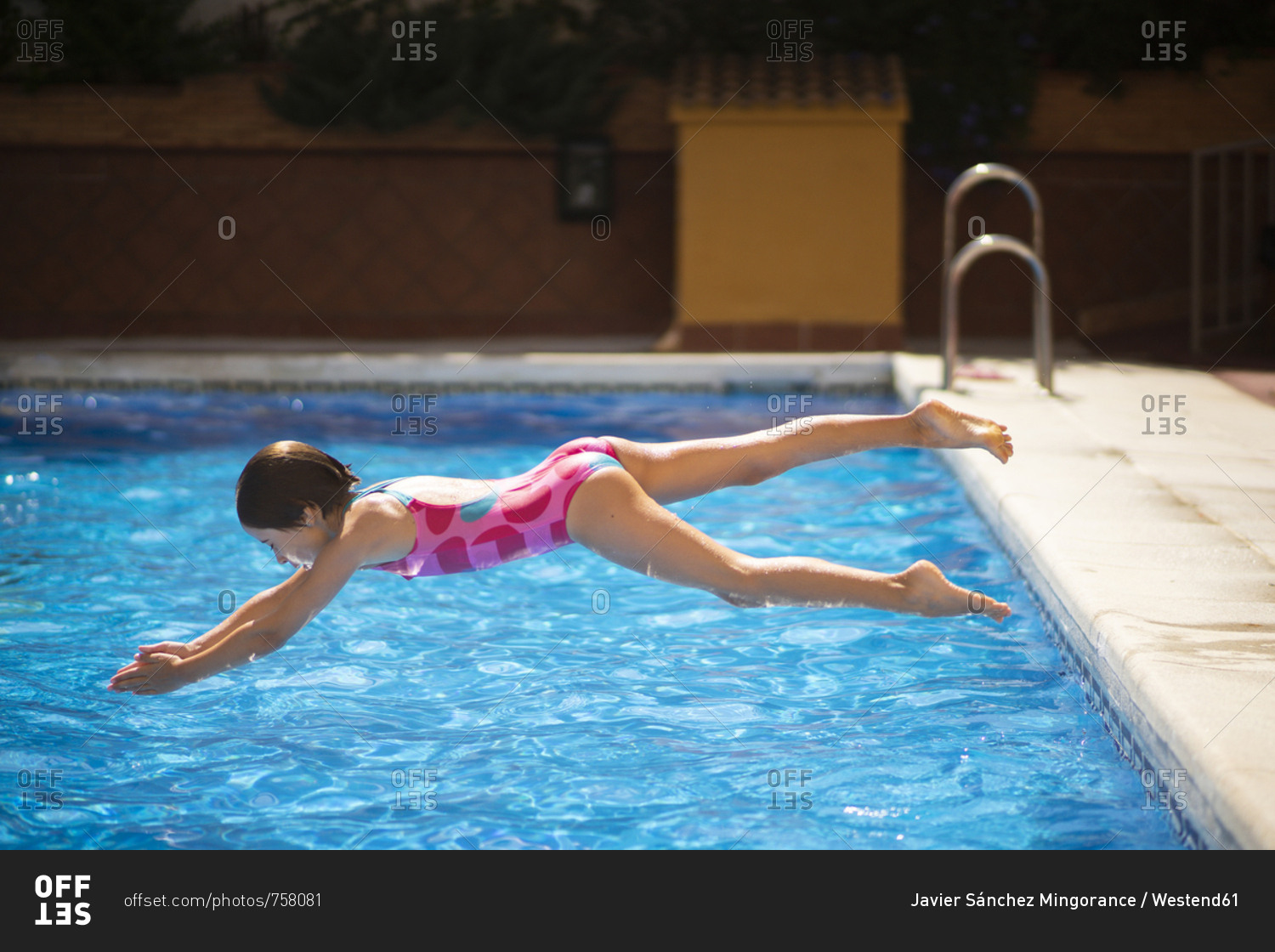 Young girl jumping head first into the pool in summer