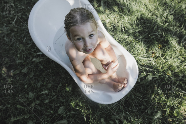 Portrait Of Little Girl Sitting In Bath Tub In Garden Stock
