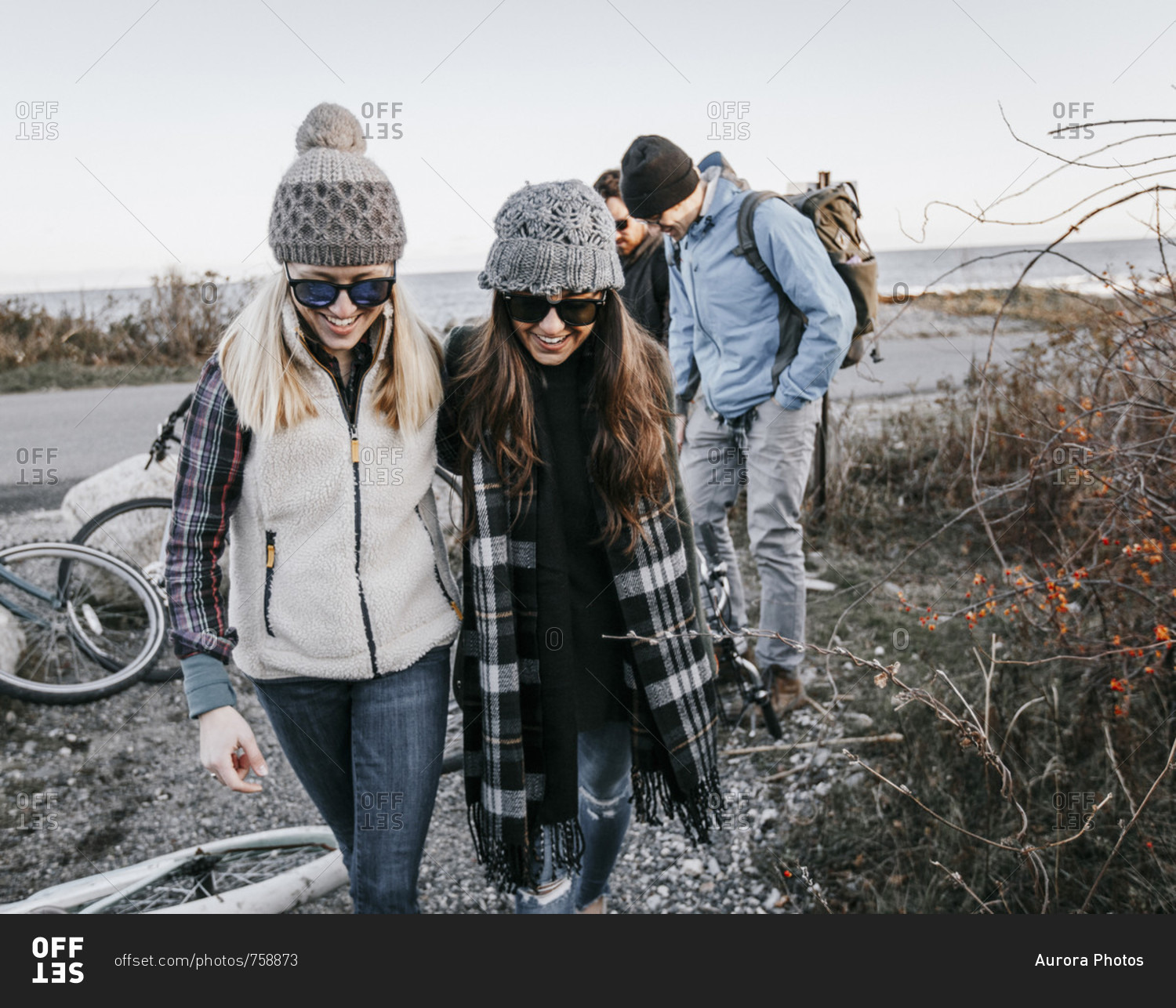 Group of adult friends leaving bicycles and walking beside bushes during hike, Portland, Maine, USA