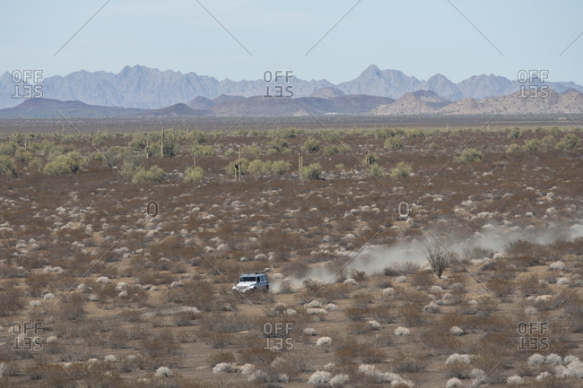 Jeep driving along path in barren desert landscape, Sonora, Mexico