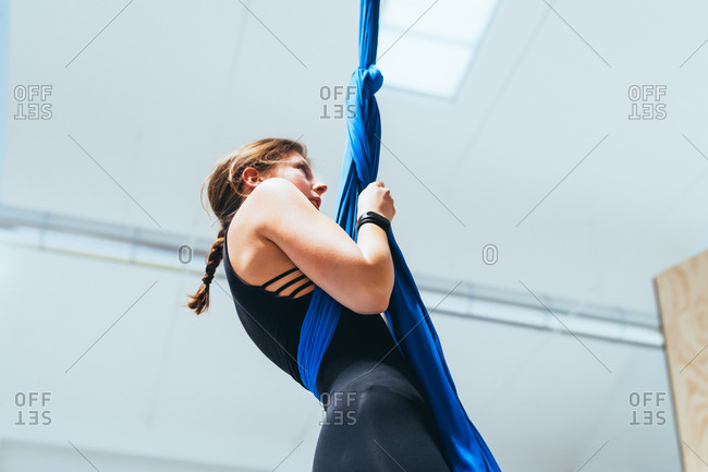 Young woman aerial acrobat hanging wrapped in silk rope - acrobat, circus, active lifestyle concept