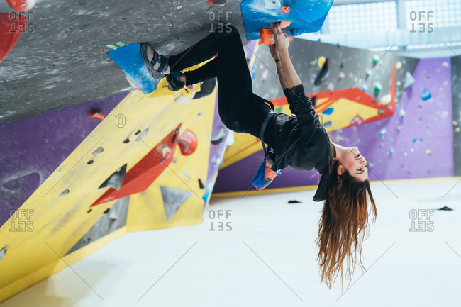 Two young women climbing rock wall indoor - healthy lifestyle, sport, climbing concept