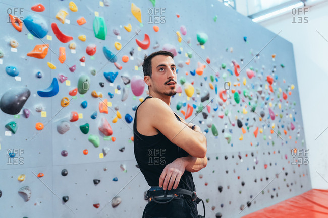 Young man climbing rock wall indoor - healthy lifestyle, sport, climbing concept