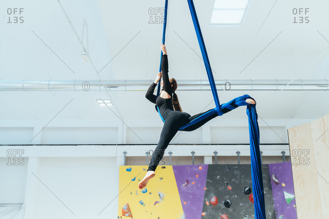Young woman climbing rock wall indoor - sportive, athletic, balance concept