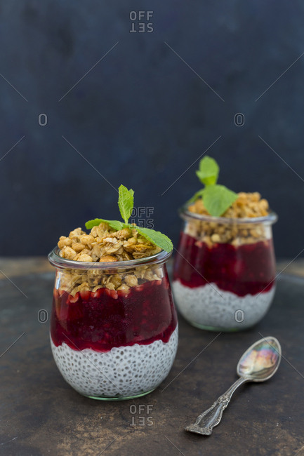 Two glasses of chia pudding with coconut milk- red fruit jelly and peanut granola topping