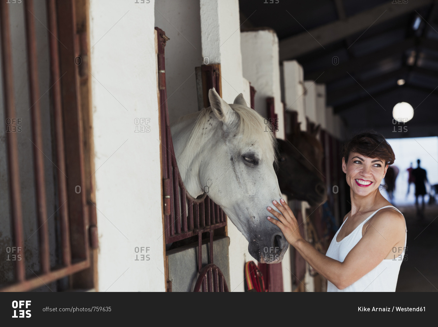 Portrait of happy woman stroking horse in stable