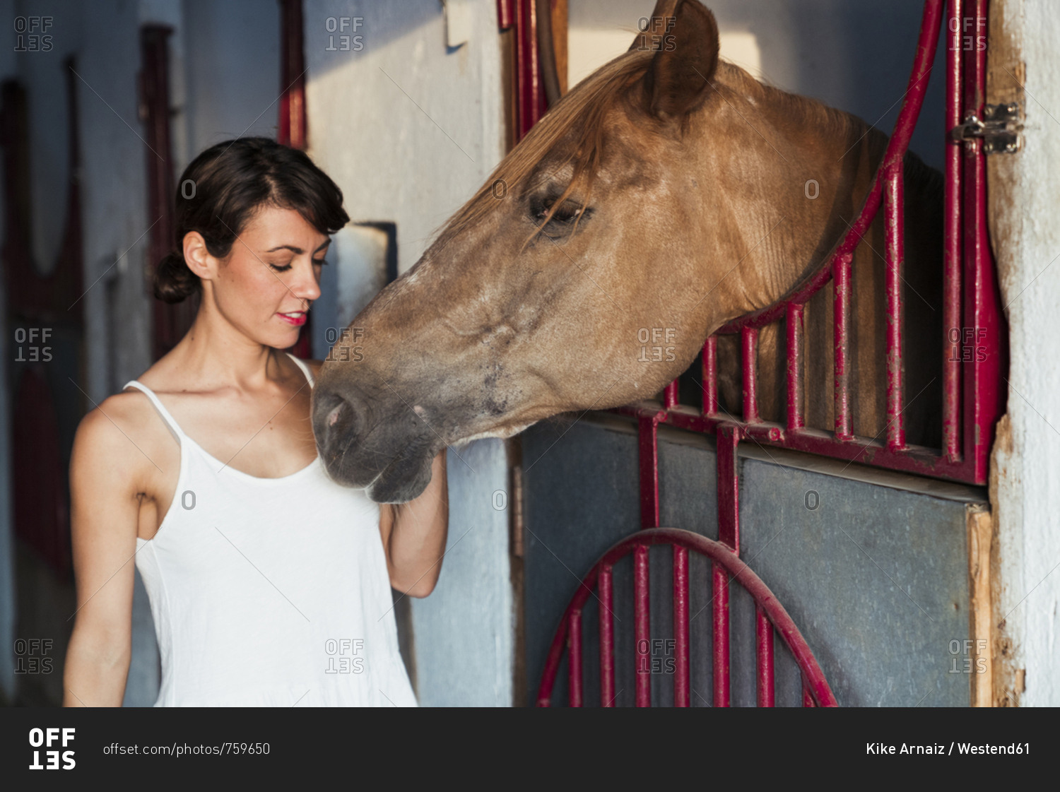 Portrait of woman stroking horse in stable