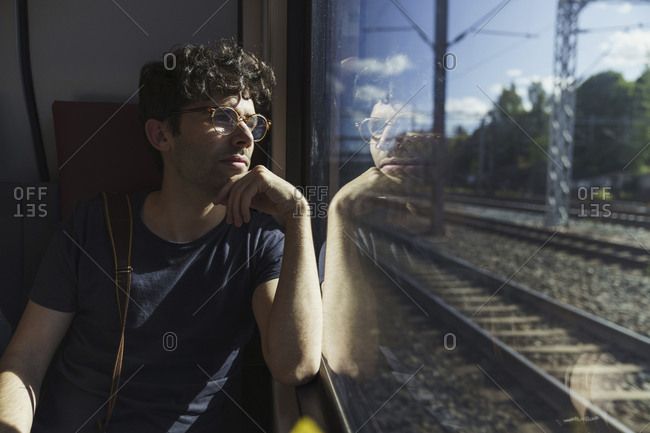 Man traveling by train looking out of window