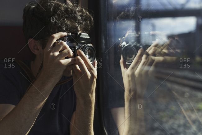 Man traveling by train taking picture with old-fashioned camera