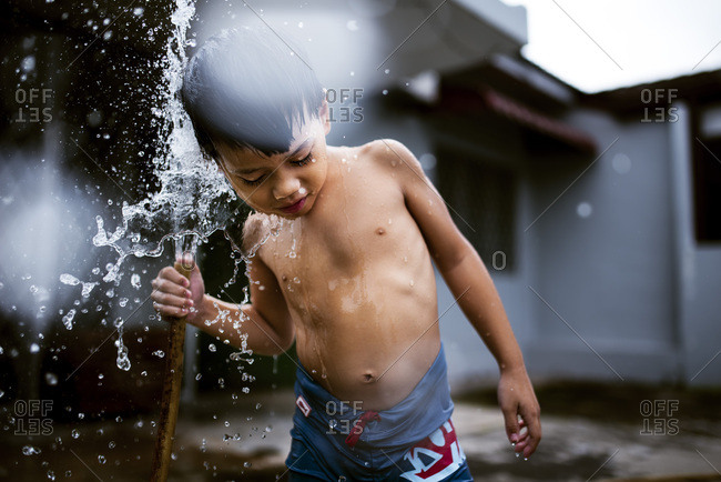 Boy playing in the water from a hose
