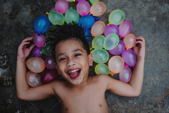 Laughing boy surrounded by colorful water balloons