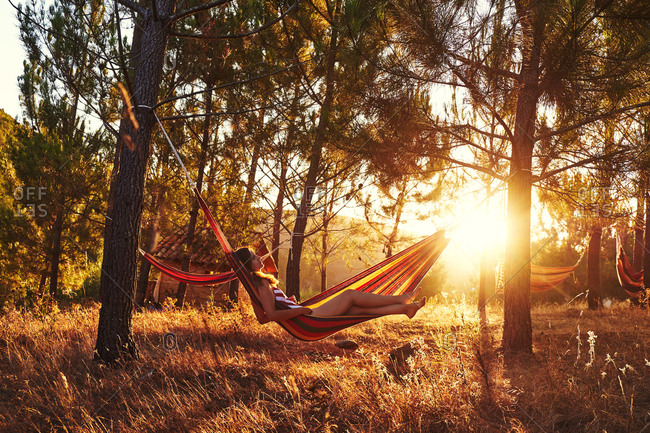 Woman lying in hammock at sunny woods