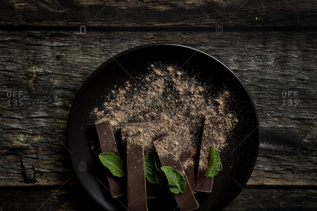 Chocolate with red chili peppers, mint and raspberries on dark background. Flat lay