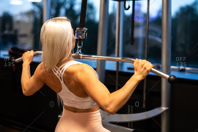 Muscular female fitness model exercising on a lat pull down