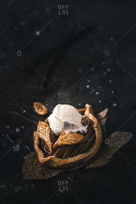 Closeup shot of yummy bun with ball of sweet ice-cream lying on piece of leaf-shaped parchment